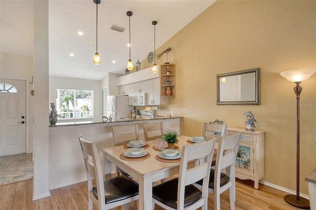 dining space with vaulted ceiling and light hardwood / wood-style flooring