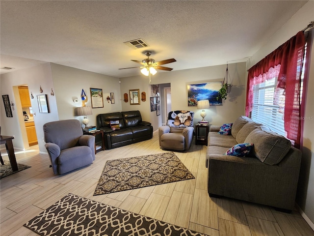 living room featuring ceiling fan and a textured ceiling