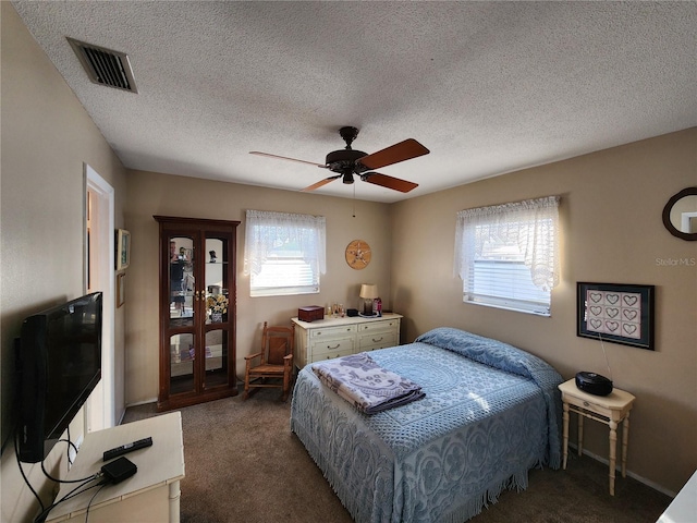 carpeted bedroom featuring ceiling fan and a textured ceiling