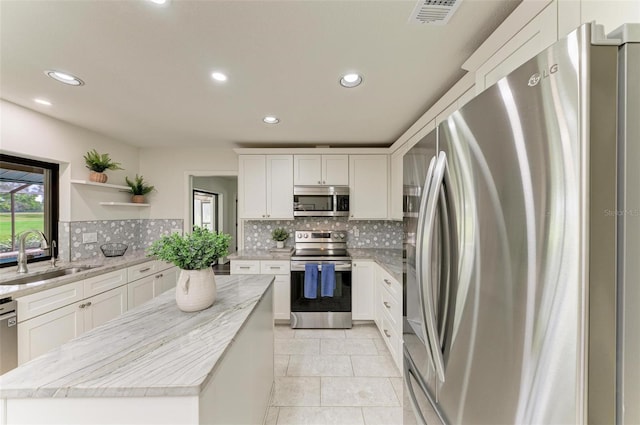 kitchen with sink, stainless steel appliances, white cabinets, and a kitchen island