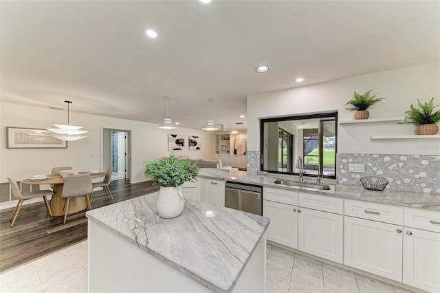 kitchen with sink, a center island, stainless steel dishwasher, pendant lighting, and white cabinets