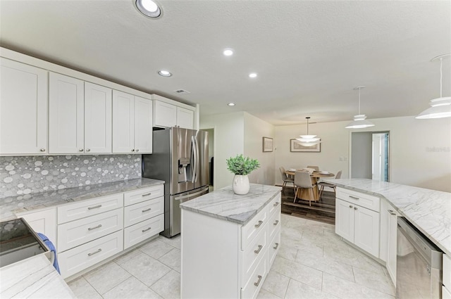 kitchen with pendant lighting, white cabinetry, appliances with stainless steel finishes, and light stone counters