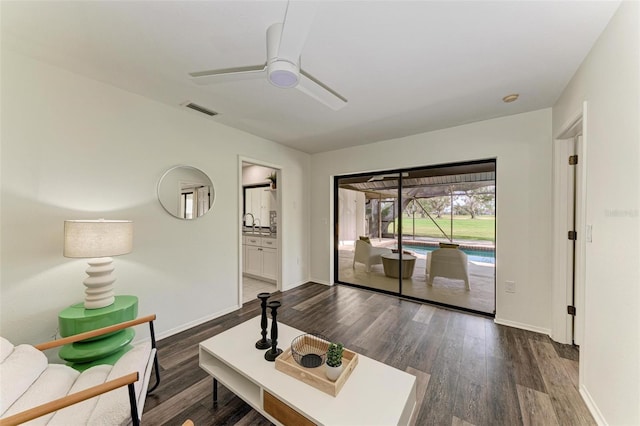 living room featuring dark wood-type flooring and ceiling fan