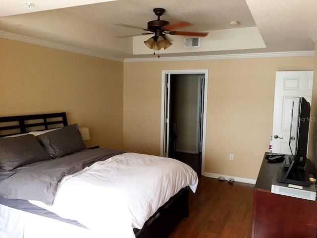 bedroom featuring ornamental molding, dark hardwood / wood-style floors, ceiling fan, and a tray ceiling