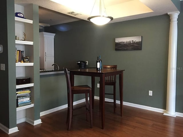 dining area with decorative columns, dark hardwood / wood-style floors, sink, and built in features