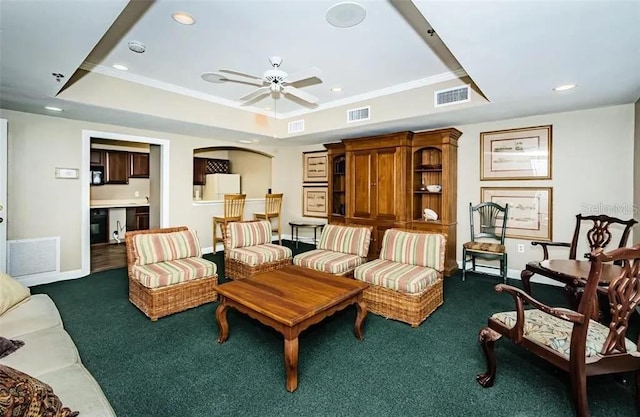 carpeted living room with crown molding, ceiling fan, and a tray ceiling