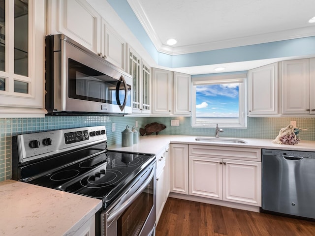 kitchen featuring sink, ornamental molding, stainless steel appliances, and white cabinets