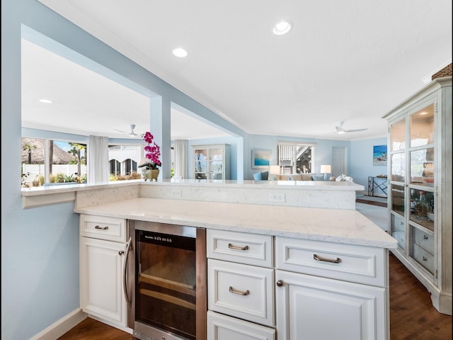 kitchen featuring white cabinets, light stone countertops, wine cooler, and kitchen peninsula