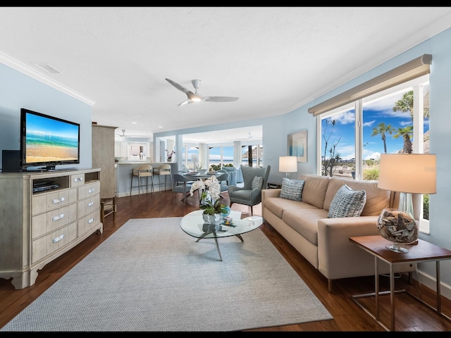 living room with crown molding, ceiling fan, and dark wood-type flooring