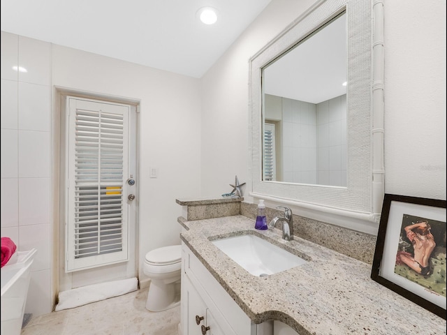 bathroom featuring vanity, a tub, and toilet