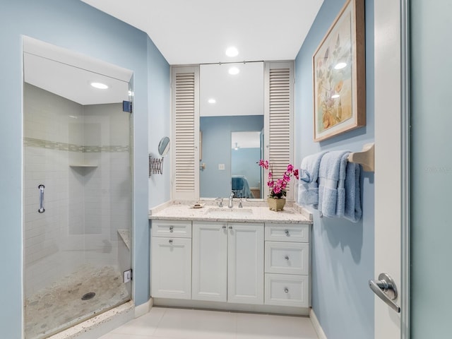 bathroom with a shower with door, vanity, and tile patterned floors