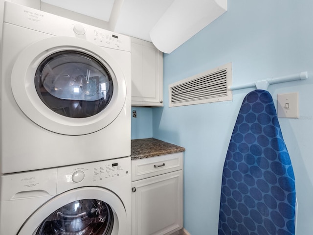 laundry area featuring stacked washer and dryer and cabinets