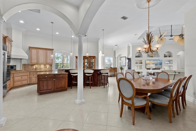 tiled dining space featuring an inviting chandelier, built in features, and decorative columns