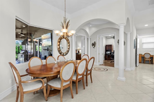 dining space featuring ceiling fan with notable chandelier, light tile patterned flooring, decorative columns, and a high ceiling