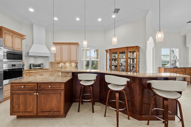 kitchen with a spacious island, custom exhaust hood, plenty of natural light, pendant lighting, and backsplash