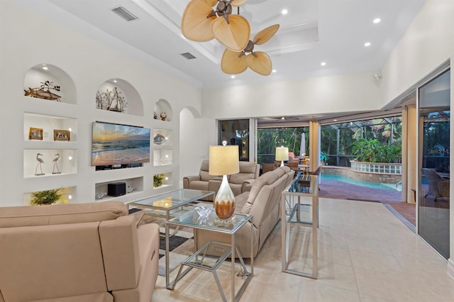 tiled living room featuring ceiling fan, built in features, and a towering ceiling