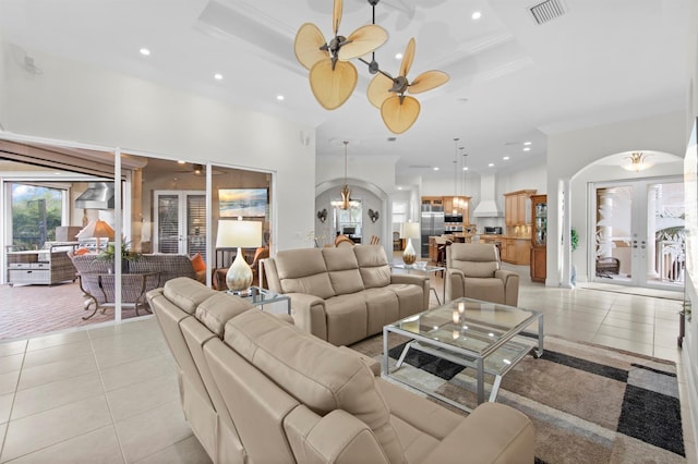 living room featuring french doors, ornamental molding, light tile patterned flooring, and ceiling fan with notable chandelier