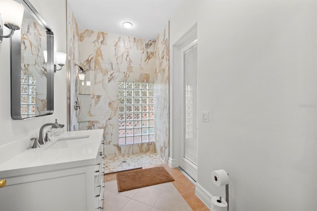 bathroom with a tile shower, vanity, and tile patterned floors