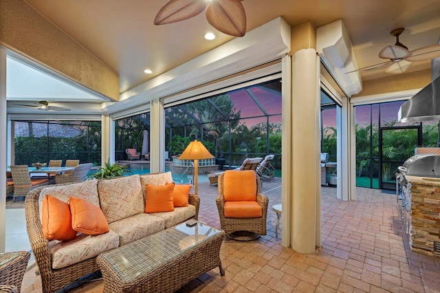 patio terrace at dusk featuring ceiling fan, area for grilling, an outdoor living space, and a lanai