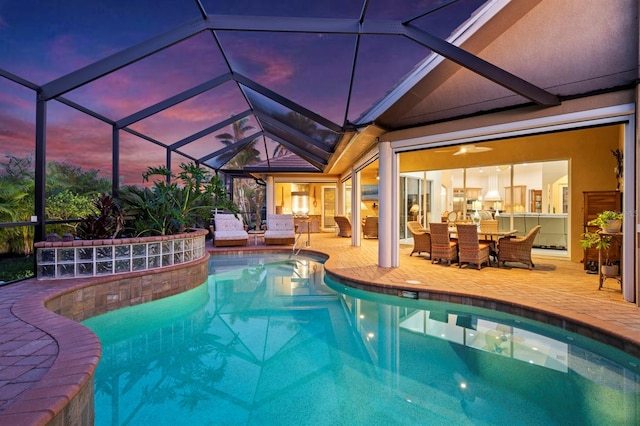 pool at dusk with a patio area, ceiling fan, and glass enclosure