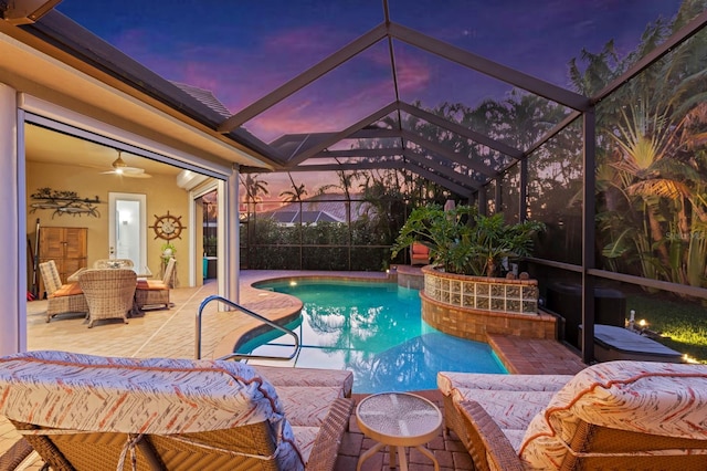 pool at dusk featuring a lanai, ceiling fan, and a patio area