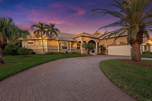 mediterranean / spanish home featuring a garage and a lawn