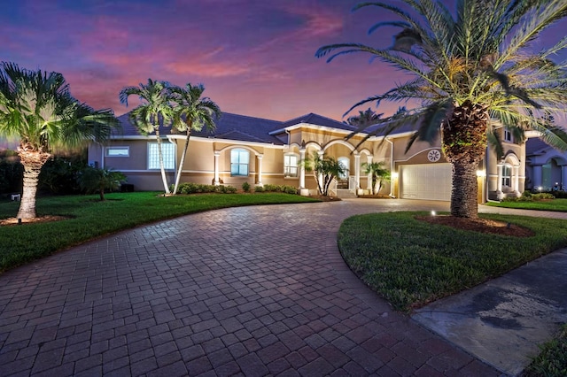 mediterranean / spanish-style house featuring a garage and a lawn