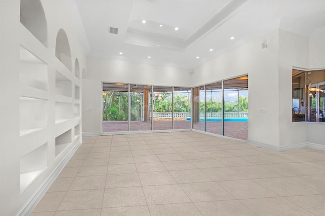 interior space with built in shelves, a towering ceiling, a healthy amount of sunlight, and crown molding