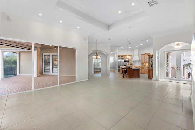 unfurnished living room with ornamental molding, light tile patterned floors, and a tray ceiling