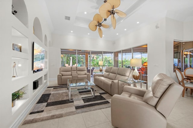 tiled living room featuring a towering ceiling, ornamental molding, and ceiling fan