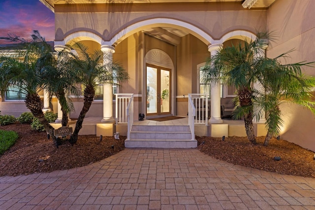 doorway to property featuring french doors, a porch, and stucco siding