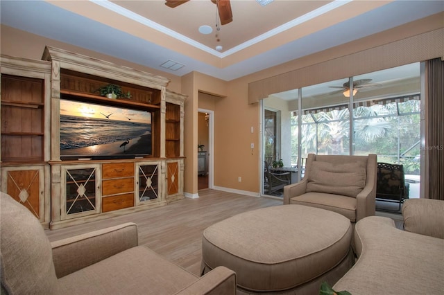 living room featuring a raised ceiling, ornamental molding, ceiling fan, and light hardwood / wood-style floors