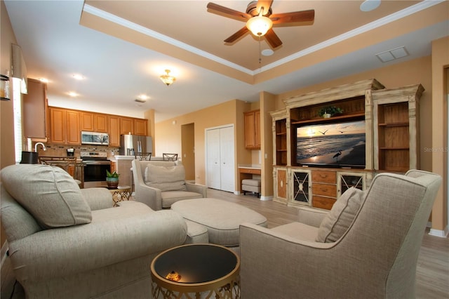 living room with a raised ceiling, crown molding, and light hardwood / wood-style floors