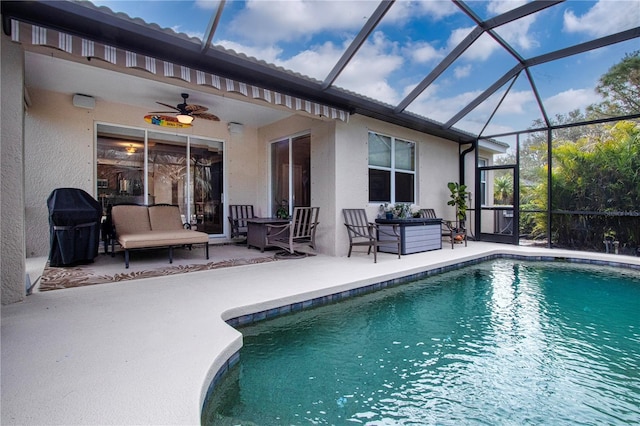 view of pool featuring grilling area, a patio area, ceiling fan, and glass enclosure