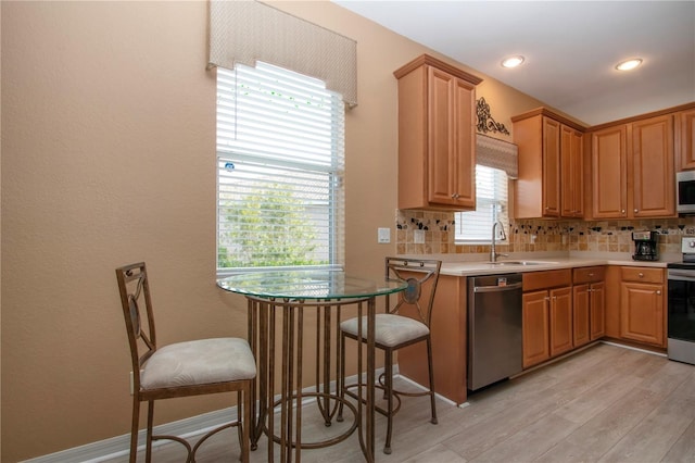 kitchen featuring appliances with stainless steel finishes, sink, backsplash, and light hardwood / wood-style flooring