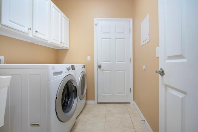 clothes washing area with cabinets, washing machine and dryer, and light tile patterned flooring