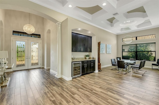 interior space featuring wine cooler, decorative light fixtures, light hardwood / wood-style floors, and a high ceiling