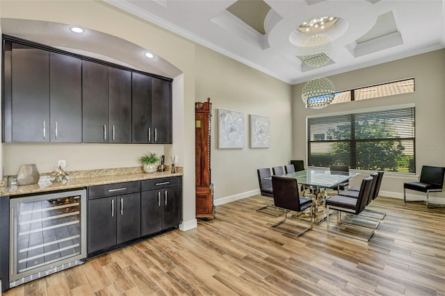 dining room featuring indoor bar, wine cooler, ornamental molding, coffered ceiling, and light hardwood / wood-style floors