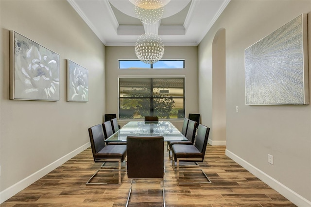 dining space with an inviting chandelier, a tray ceiling, crown molding, and hardwood / wood-style flooring