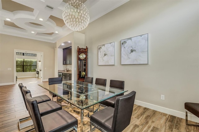 dining area with coffered ceiling, ornamental molding, light hardwood / wood-style floors, and an inviting chandelier