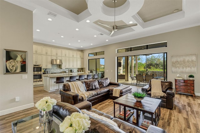 living room with ornamental molding, coffered ceiling, and light hardwood / wood-style flooring