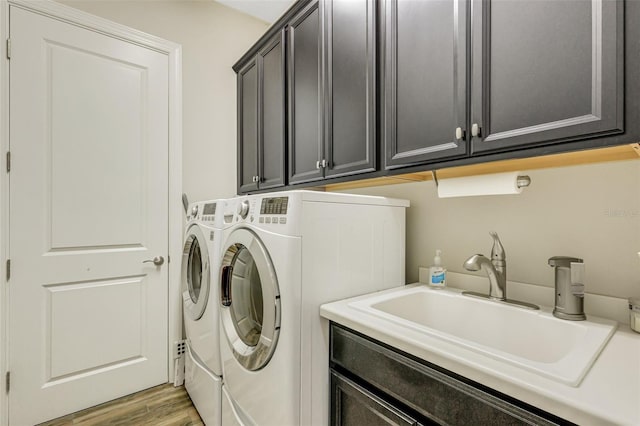 laundry room with hardwood / wood-style flooring, cabinets, sink, and washing machine and dryer