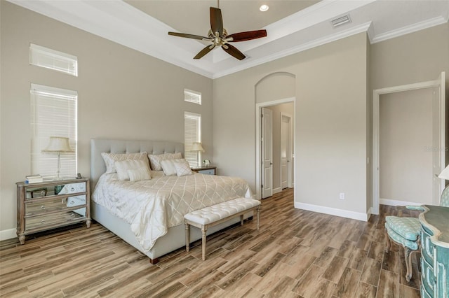 bedroom with hardwood / wood-style floors, crown molding, a raised ceiling, and ceiling fan