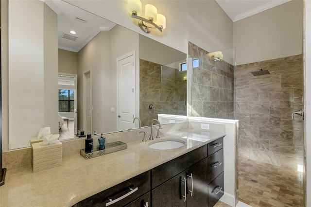 bathroom featuring crown molding, tiled shower, and vanity