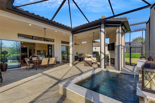 view of pool with ceiling fan, pool water feature, a patio, and an outdoor fireplace