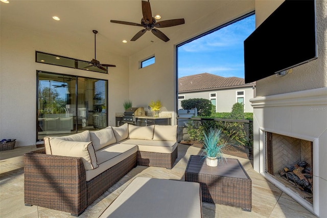 view of patio featuring ceiling fan, a grill, an outdoor living space with a fireplace, and exterior kitchen