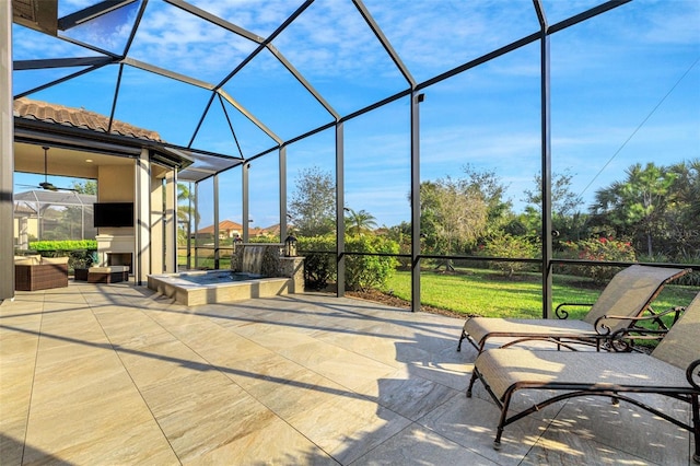 view of patio featuring a lanai, an outdoor hot tub, and a fireplace