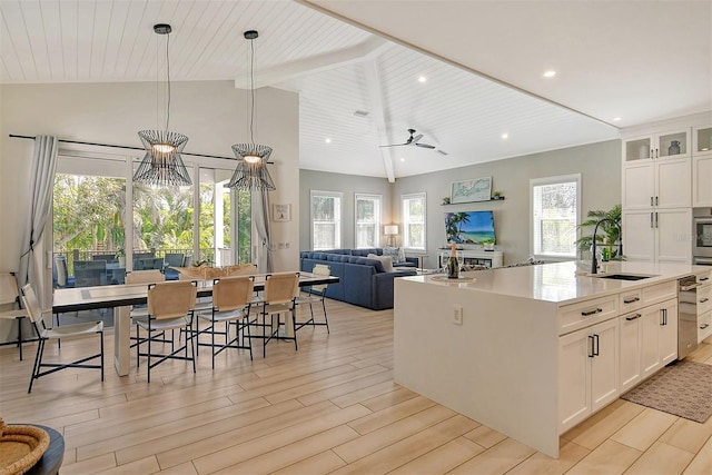 kitchen featuring an island with sink, sink, pendant lighting, and white cabinets