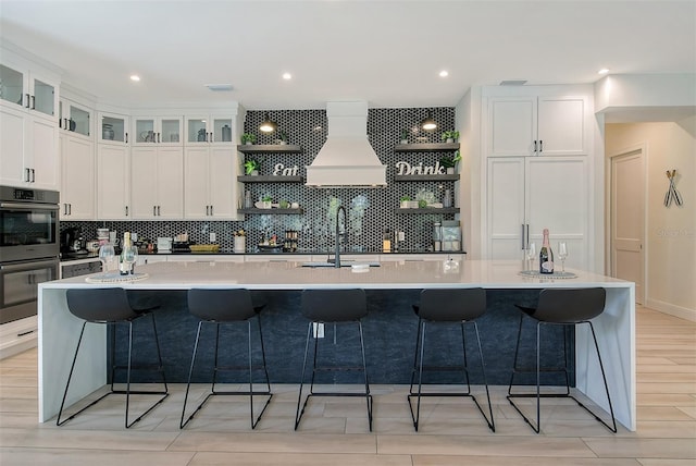 kitchen featuring stainless steel double oven, a large island, and custom exhaust hood