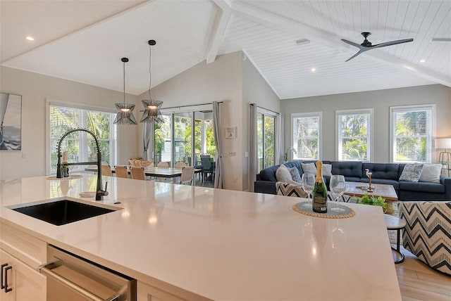 kitchen with sink, light hardwood / wood-style flooring, hanging light fixtures, lofted ceiling with beams, and stainless steel dishwasher